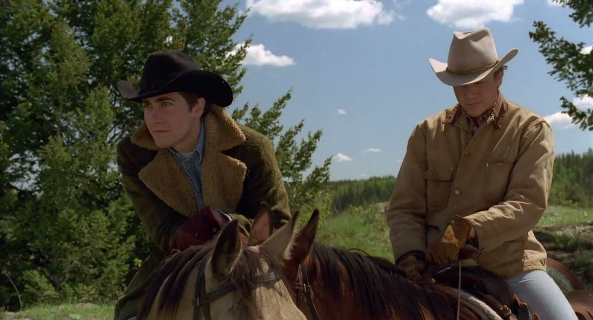 Jake Gyllenhaal in a black cowboy hat and Heath Ledger in a tan hat on horseback in Brokeback Mountain