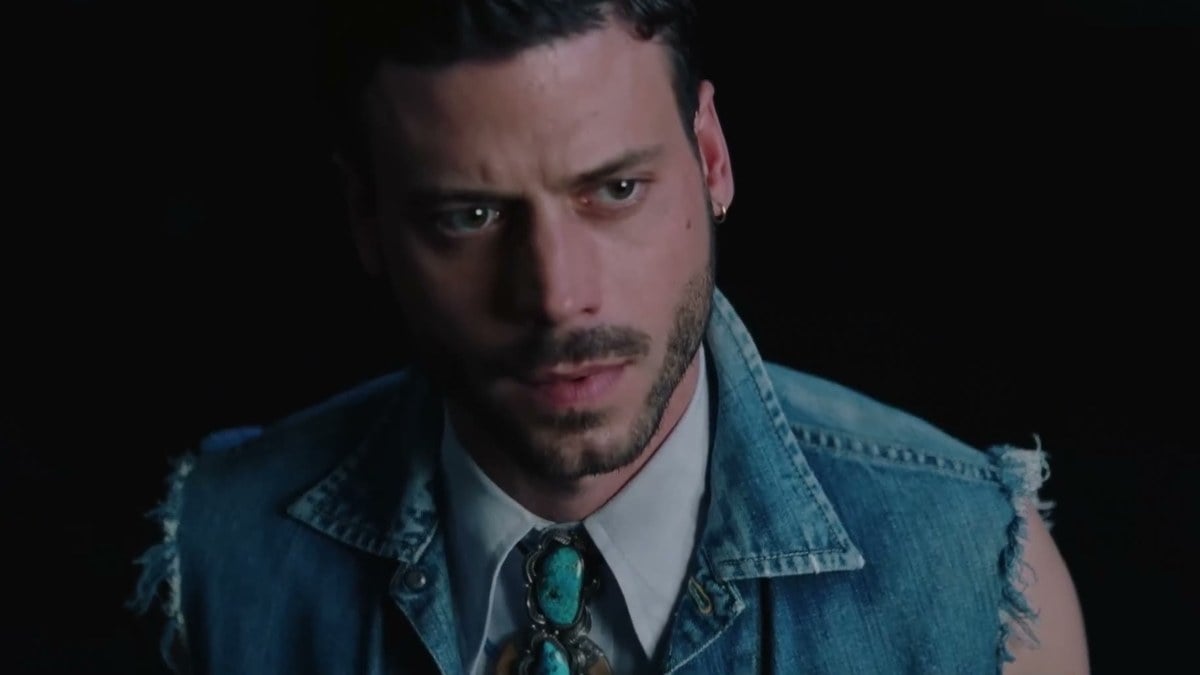 François Arnaud in a sleeveless denim vest and turquoise bolo tie