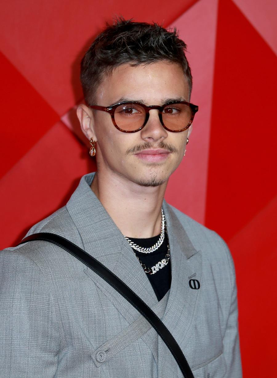 Romeo Beckham in tinted glasses, a grey check suit and chains at The Fashion Awards in London