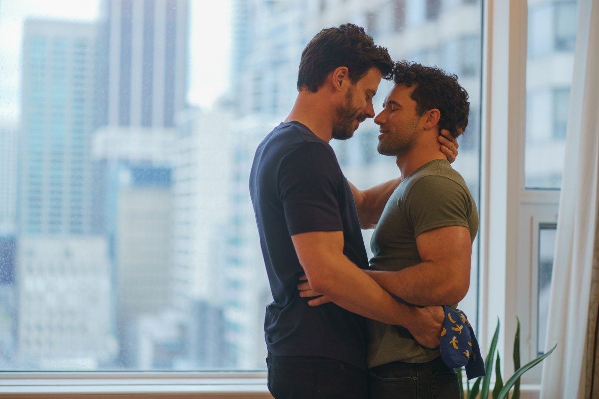 François Arnaud as Scott Hunter and Robbie G.K. as Kip Grady embracing by a window in Heated Rivalry