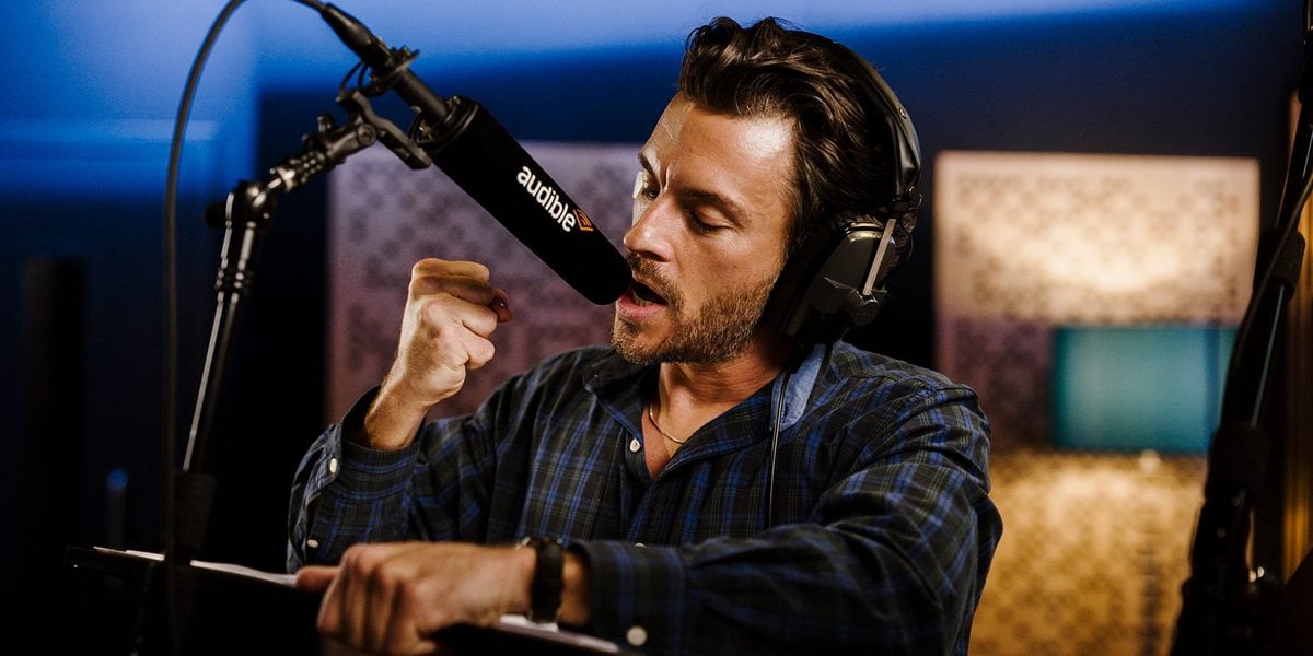 Jonathan Bailey leaning into the microphone with a clenched fist mid-performance
