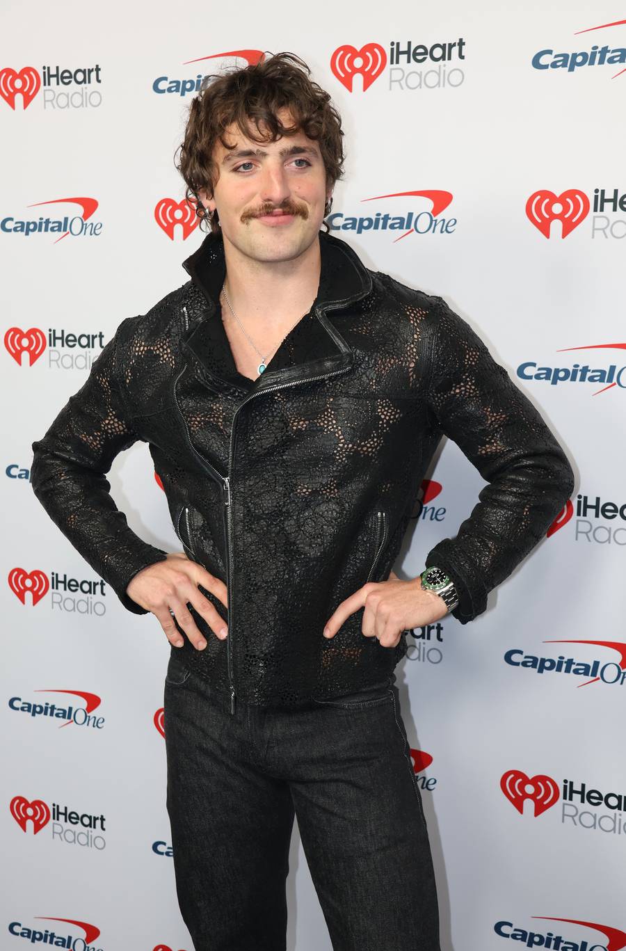 Benson Boone in a black perforated leather jacket, hands on hips, at the iHeartRadio Music Festival