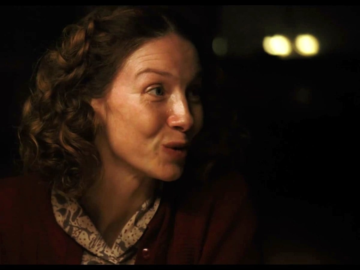 Caitriona Balfe as Louise talking at a candlelit dinner table
