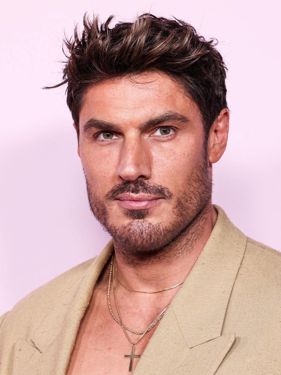 Chris Appleton in a beige blazer on a pink red-carpet backdrop