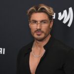 Chris Appleton in glasses and an open black shirt on the red carpet