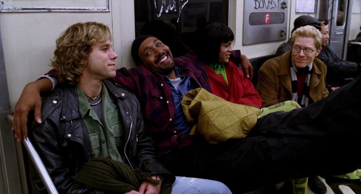 Adam Pascal, Jesse L. Martin with his arm around Wilson Jermaine Heredia as Angel in a black bob wig, and Anthony Rapp riding the subway in the 2005 film Rent