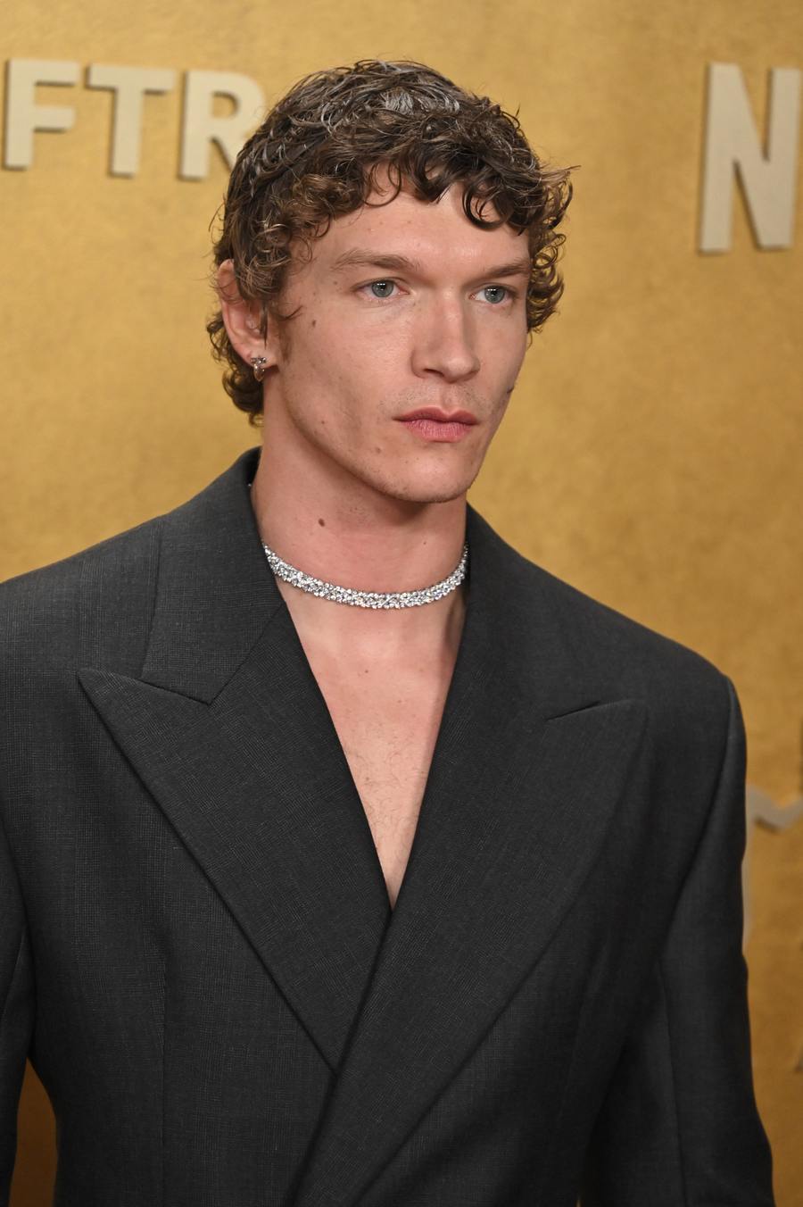 Connor Storrie in a black double-breasted suit and diamond necklace at the Actor Awards