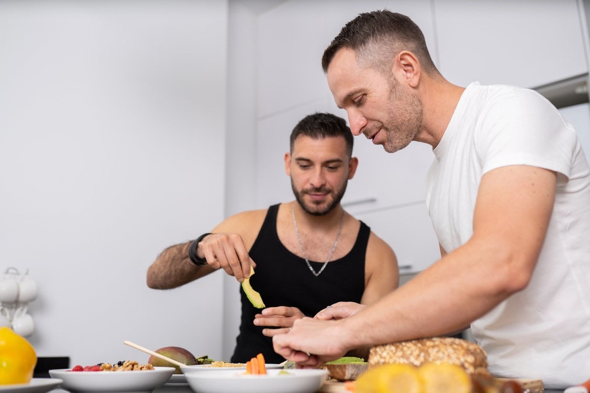 Two men preparing food together at a kitchen counter