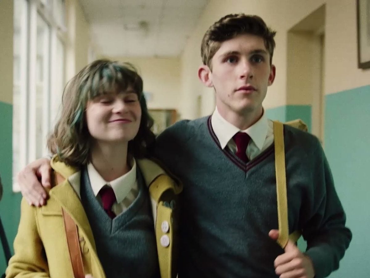 Lola Petticrew and Fionn O’Shea in school uniforms walking arm in arm down a school corridor in Dating Amber