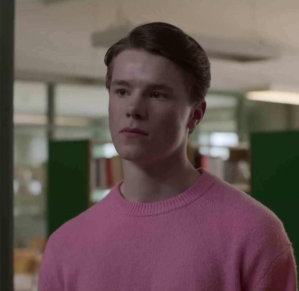 Edvin Ryding as Prince Wilhelm in a pink sweater in a school library