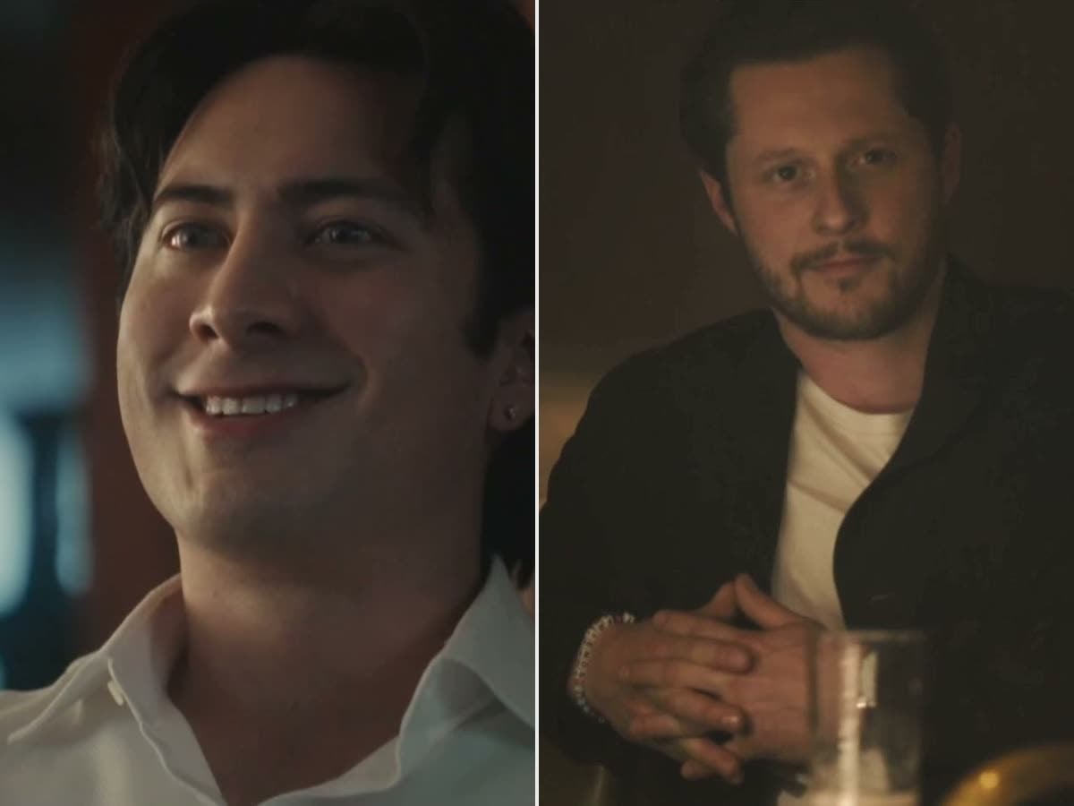 Hudson Williams smiling in a white shirt as Henry Park, beside Noah Reid as Rapp at a candlelit bar in Yaga
