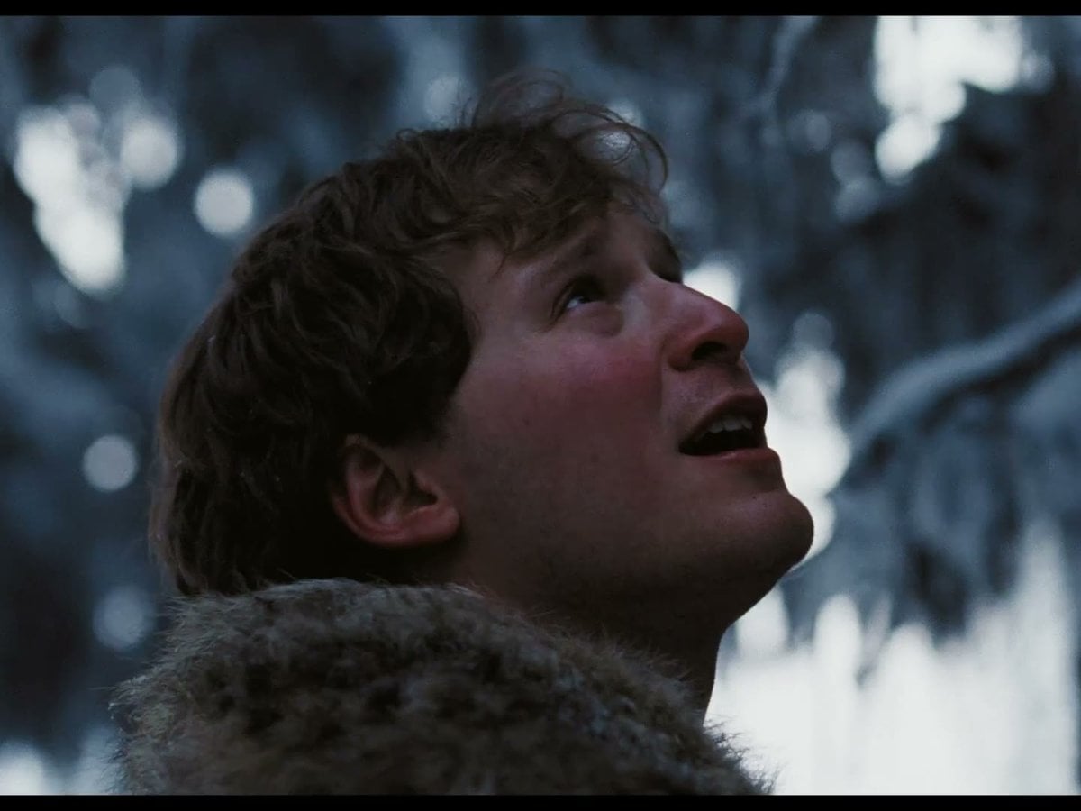 Fred Hechinger as Mike in a fur collar looking up at snowy trees