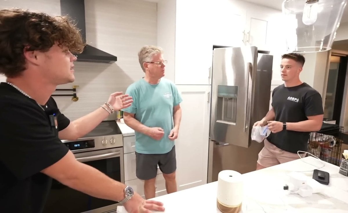 Jack Doherty with curly hair talking in a kitchen, with Michael Doherty in a black T-shirt standing on the right