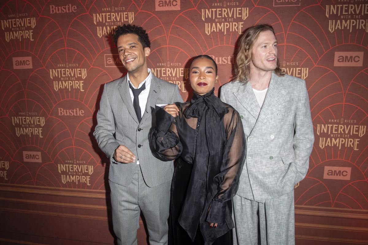 Jacob Anderson and Sam Reid in grey suits at the Interview with the Vampire season 2 premiere, with a woman between them