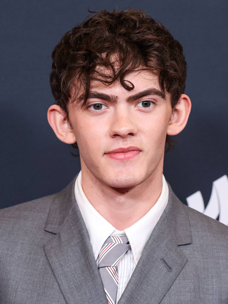 Joe Locke in a gray suit and striped tie on a red carpet