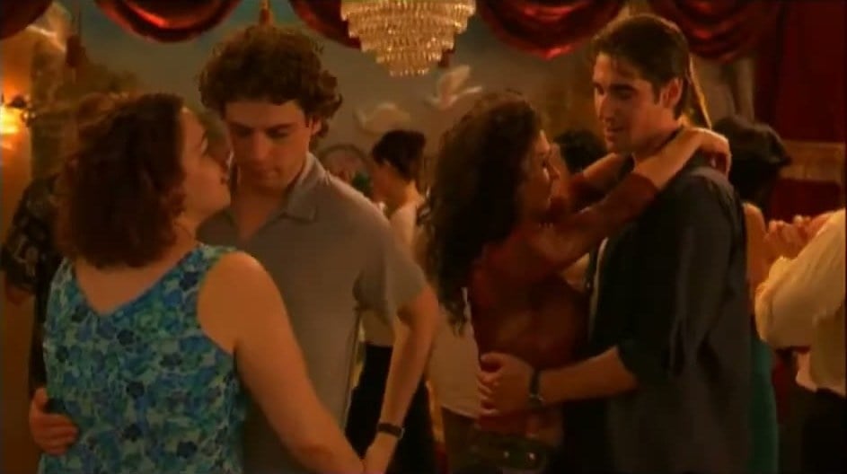 Luke Kirby and Peter Miller dancing with women at a crowded banquet hall party in Mambo Italiano