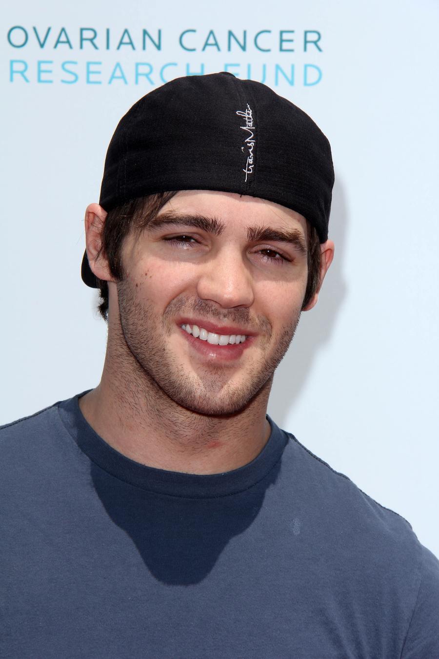 Steven R. McQueen in a backwards black cap and gray T-shirt, smiling