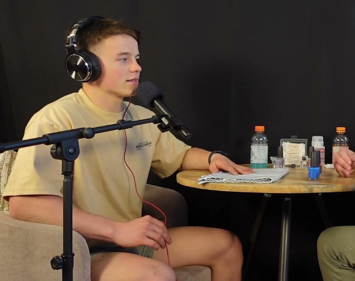 Michael Doherty in headphones and a yellow T-shirt talking into a microphone on a podcast set