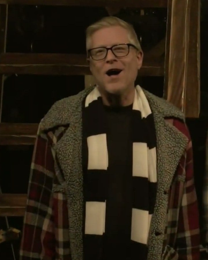 Anthony Rapp in glasses and a black-and-white striped scarf singing on stage at the Rent 30th anniversary concert
