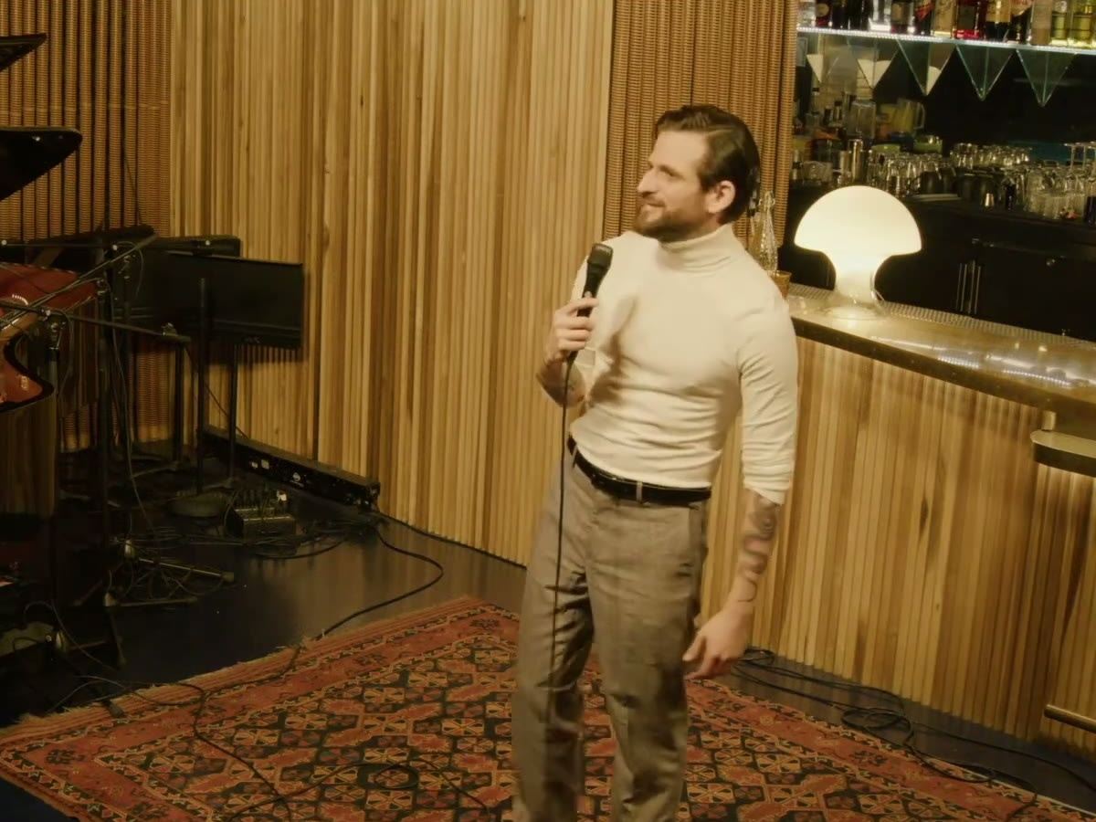 Richard Cortez in a white turtleneck singing into a microphone at a jazz club