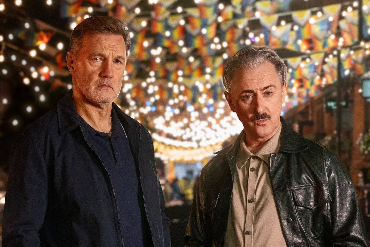 David Morrissey and Alan Cumming in Tip Toe, standing under rainbow bunting and string lights on a Manchester street at night