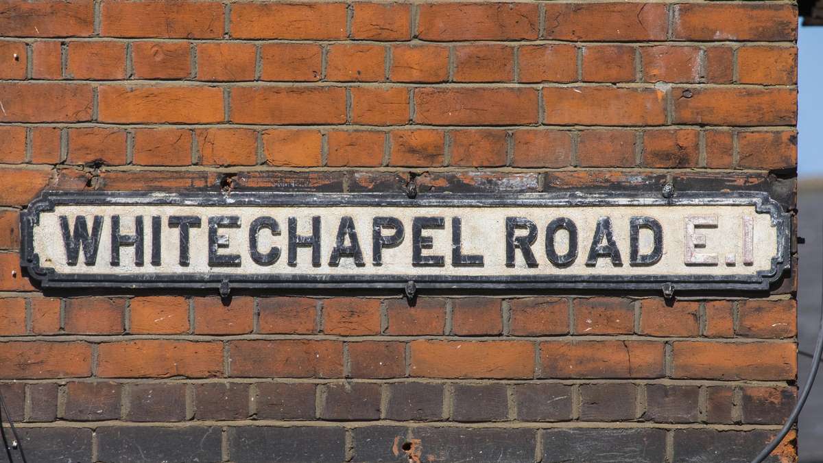 Whitechapel Road E1 street sign on a brick wall in east London
